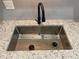 Close-up of a modern stainless steel kitchen sink with granite countertops and a modern faucet at 3228 Shadow Walk Ln, Tucker, GA 30084