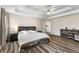 Spacious main bedroom featuring a tray ceiling, ceiling fan, wood accent furniture and luxury vinyl plank flooring at 502 Stoneland Pl, Lawrenceville, GA 30046