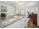 Bathroom featuring double sinks with granite counters, white cabinets and view into the bedroom at 3597 Embry Cir, Atlanta, GA 30341