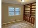 A cozy bedroom includes a large window and a wall of built-in wooden shelving and cabinets at 951 Bingham Ln, Stone Mountain, GA 30083