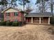 Charming brick home with a covered porch, red shutters, and mature landscaping at 951 Bingham Ln, Stone Mountain, GA 30083