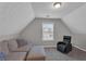 Cozy attic space featuring a comfortable couch, ottoman, and chair, with a window providing natural light at 3248 Meadow Point Dr, Snellville, GA 30039