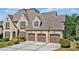 Elegant brick home boasting a three-car garage, dormer windows, and lush green lawn at 1965 Carlotta Ct, Atlanta, GA 30345