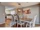 Bright dining area featuring hardwood floors, modern lighting fixture, and adjacent kitchen with white cabinetry at 3085 Nappa Trl, Stone Mountain, GA 30087