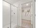 White tiled shower with a sliding glass door and a view of the walk-in closet at 5441 Flat Rock Point Pt, Stonecrest, GA 30038