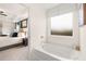 Bathroom with a tub and large window, and a glimpse into the main bedroom at 5441 Flat Rock Point Pt, Stonecrest, GA 30038