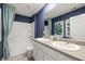 Bathroom showcasing double sinks, blue walls, white cabinetry, and tub with patterned curtain at 5441 Flat Rock Point Pt, Stonecrest, GA 30038