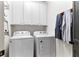 Bright laundry room features a white washer and dryer, along with ample cabinet space for storage at 5705 Odell St, Cumming, GA 30040