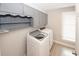 Efficient laundry room with modern washer and dryer, shelving, storage cabinets, and a window for natural light at 4995 Greentree Trl, College Park, GA 30349