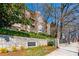 Brick apartment building, The Carlton, with balconies, manicured landscaping, and stone sign under a blue sky at 825 Highland Ln # 1105, Atlanta, GA 30306
