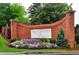 Community entrance adorned with brick pillars, lush flowers, and 