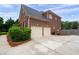 Side view of the brick home featuring a two-car garage and well-kept landscaping at 235 Rippling Nw Dr, Marietta, GA 30064