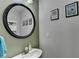 Powder room features modern fixtures, a round mirror and neutral colors at 1171 Pine Acre Dr, Sugar Hill, GA 30518