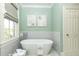 Cozy bathroom with a freestanding tub, soft green walls, and a bright window at 3448 Paces Ferry Cir, Smyrna, GA 30080