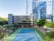 Outdoor tennis court with blue and green surface, surrounded by lush greenery and modern buildings at 3445 Stratford Ne Rd # 1605, Atlanta, GA 30326