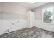 Well-lit laundry room with sleek wood-look floors, a large window, and ample storage cabinets at 2984 Berry Rd, Loganville, GA 30052