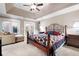 Main bedroom featuring a tray ceiling, ceiling fan, access to the exterior, and an ornate bed frame at 330 Todwick Dr, Roswell, GA 30075