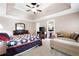Spacious main bedroom with a tray ceiling, ceiling fan, seating area, and an attached bathroom at 330 Todwick Dr, Roswell, GA 30075