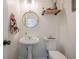 Simple half bath featuring a pedestal sink and a round mirror for guests at 9225 Wilshire Pl, Cumming, GA 30028