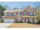 Beautiful two-story home with stone accents, red shutters, an attached garage, and a rocking chair front porch at 9225 Wilshire Pl, Cumming, GA 30028