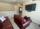 Upstairs bonus room featuring leather sofas, a large window, and a TV at 3624 Peeksville Rd, Locust Grove, GA 30248