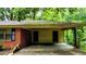 View of the covered carport and two doors, with a glimpse of the surrounding greenery at 6470 Sherwood Trl, Austell, GA 30168