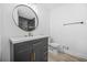 Modern bathroom vanity features sleek black cabinets, gold hardware, white countertops, and oval mirror at 897 Marie Lane Sw Ln, Conyers, GA 30094