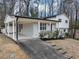 Split-level home with black and white trim, and a car port on a grassy lot with trees in the background at 847 Magna Carta Nw Dr, Atlanta, GA 30318