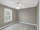 This bedroom features gray walls, a ceiling fan, woodgrain floors and a sun-filled window overlooking the yard at 414 Shadetree Ln, Lawrenceville, GA 30044