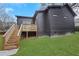 View of the black, modern home showcasing a spacious, green lawn and wooden deck with stairs at 875 Center Hill Nw Ave, Atlanta, GA 30318