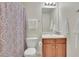 Well-lit bathroom featuring a vanity with wooden cabinets, toilet, mirror and patterned shower curtain at 318 Farmbrook Pass, Canton, GA 30115