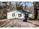 A quaint single-story home with white siding, black shutters, an asphalt driveway, and mature trees at 100 Daisy Cir, Canton, GA 30114