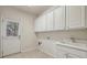 Bright laundry room with white cabinets, sink, tile floor, and exterior door at 1016 Parkmont Way, Decatur, GA 30033