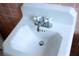 Close-up of a white porcelain sink with cross-handle faucets against peach-tiled wall at 1624 Beatie Ave, Atlanta, GA 30310