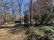 View of the driveway, covered parking, and surrounding trees and greenery on a sunny day at 5169 Oxbow Rd, Stone Mountain, GA 30087