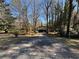 View of a long driveway leading to a covered parking area surrounded by a grassy yard and mature trees at 5169 Oxbow Rd, Stone Mountain, GA 30087