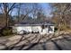 Charming white home with a dark roof and front door, surrounded by trees, and a concrete driveway at 70 Daisy Cir, Canton, GA 30114