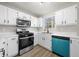 Bright kitchen showcasing stainless steel appliances, white cabinets, and a large sink beneath a sunny window at 826 Shore Dr, Lithonia, GA 30058