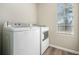 Efficient laundry area featuring modern white front load washer and dryer with a bright window at 826 Shore Dr, Lithonia, GA 30058