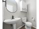 Stylish powder room with pedestal sink, round mirror, modern faucet and toilet at 826 Shore Dr, Lithonia, GA 30058