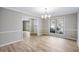 Bright dining room featuring wood floors, a modern chandelier, and large windows overlooking the landscaped yard at 1107 Sanfords Walk, Tucker, GA 30084