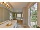 Well-lit bathroom with double vanity, soaking tub, and large window with view of lush landscape at 5080 Firelight Ln, Alpharetta, GA 30022