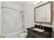 Bathroom featuring a shower and bathtub combo, granite vanity, and a framed mirror, complemented by warm lighting at 611 Irwin Ne St, Atlanta, GA 30312