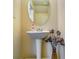 Cozy powder room featuring a pedestal sink, decorative mirror, neutral walls, and stylish accents at 1155 Magnolia Gardens Walk, Mcdonough, GA 30253