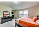Comfortable bedroom featuring a black dresser, a bed with orange bedding, and natural light streaming through the windows at 1155 Magnolia Gardens Walk, Mcdonough, GA 30253
