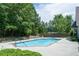 View of the community pool with a fence, lounge chairs, and surrounded by mature trees at 3916 Abbott Way # 2, Powder Springs, GA 30127