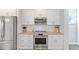 Kitchen featuring stainless steel appliances, white cabinets, and a tile backsplash at 8050 Tristan Way, Whitesburg, GA 30185