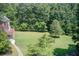 Green backyard adjoins wooded area for ultimate privacy, while a walkway leads to the home's lower level and deck at 1603 Drowning Creek Rd, Dacula, GA 30019