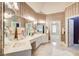 Elegant bathroom with dual sinks, decorative mirrors, and luxurious finishes; an open doorway to the bedroom at 1603 Drowning Creek Rd, Dacula, GA 30019
