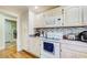 Bright kitchen featuring white appliances, light-colored cabinets, and a mosaic backsplash, next to a utility area at 1603 Drowning Creek Rd, Dacula, GA 30019